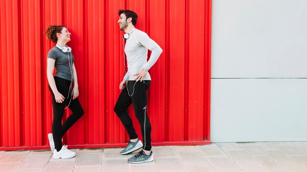 Laughing people communicating near red wall